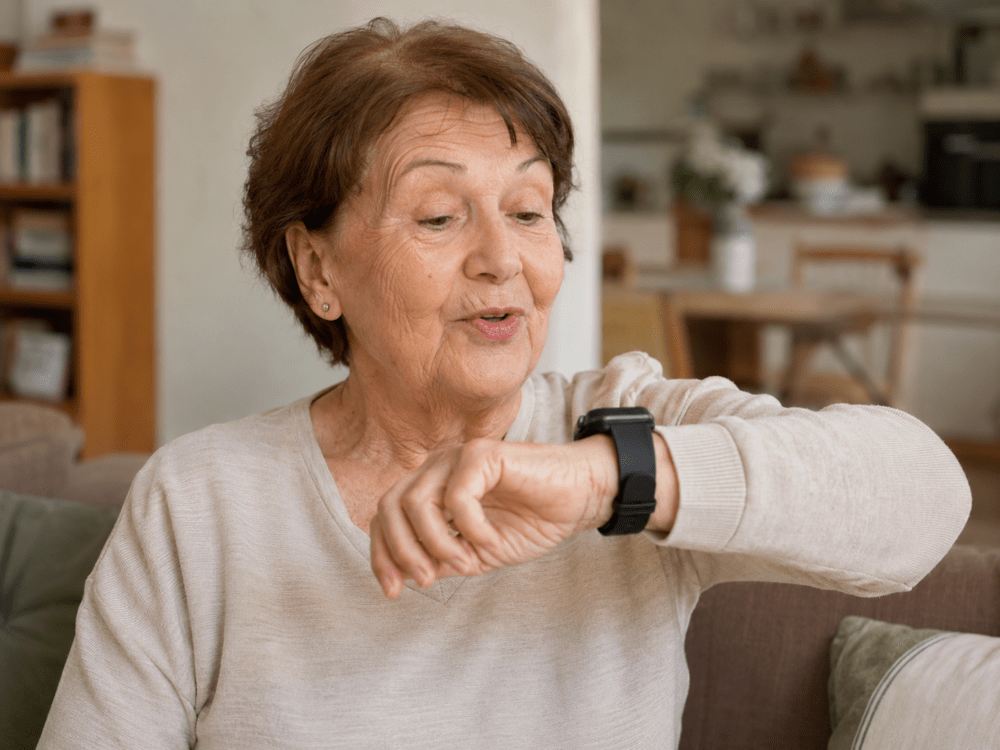 Seniorka mluví s rodinou přes hodinky Senzoor a rodina vidí polohu v aplikaci